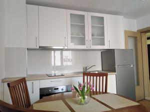 a kitchen with white cabinets and a table and chairs at Apartman Roko in Ploče