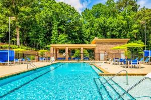 a swimming pool with tables and chairs and umbrellas at Elegant 2BR Suite in Downtown Waxhaw w. Pool 