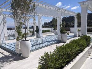 uma pérgola branca com quatro vasos brancos com plantas em Stunning 5th floor condo w/ scenic view near tran em Cuenca