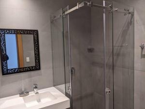 a bathroom with a shower with a sink and a mirror at Stunning 5th floor condo w/ scenic view near tran in Cuenca