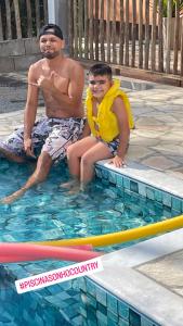 un hombre y un niño sentados en una piscina en Pousada Rural Ouro Verde, en Eldorado