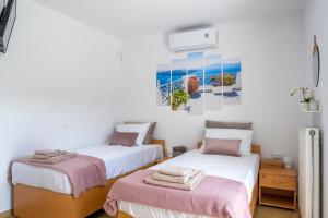 2 Betten in einem Zimmer mit weißen Wänden in der Unterkunft New Olivka House in Anavyssos