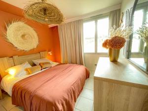 um quarto com uma parede laranja, uma cama e janelas. em Sur la plage Valentin Beach Home - T3bis em Batz-sur-Mer
