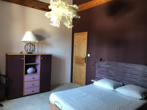 een slaapkamer met een bed, een lamp en een dressoir bij Le Moulin de Milan in Cheval-Blanc