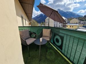 um pátio com 2 cadeiras e um guarda-sol numa varanda em Appartement 223 em Bad Aussee