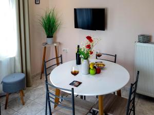 a white table with a vase of flowers and wine glasses at Villa Kalliope in Keramoti