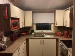 a kitchen with white cabinets and a sink and a window at Holiday Home At Seton Sands in Port Seton