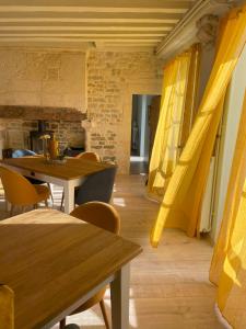 Logis de Pierre Levée في Bessines: غرفة طعام مع طاولات خشبية وستائر صفراء