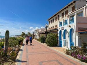 two people walking down a sidewalk next to a building at Apartamentos Be Suites Mediterráneo in Oropesa del Mar