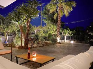 eine Terrasse mit einem Sofa, einem Tisch und Palmen in der Unterkunft Sand by Aestas Suites in Artemida