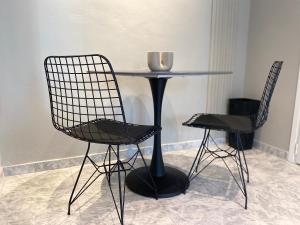 2 Stühle und ein Tisch mit einer Glasschüssel drauf in der Unterkunft Sand by Aestas Suites in Artemida