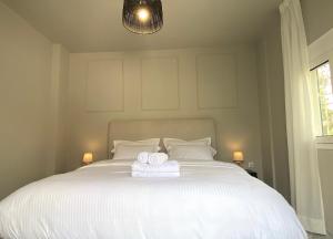 Sand by Aestas Suites في أرتيميدا: غرفة نوم بسرير ابيض عليها منشفتين