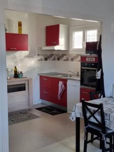 a kitchen with red cabinets and a table with a chair at Port de Riberou in Saujon