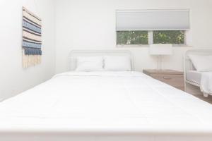 een wit bed in een witte slaapkamer met een raam bij One Bedroom Apartment - with Parking & Balcony - Heart of Wynwood in Miami