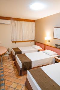 a hotel room with four beds and a table at Black Stream Hotel in Ribeirão Preto