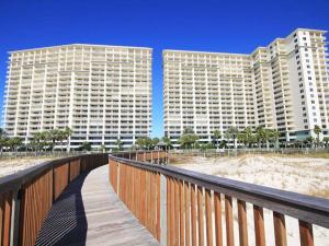 a wooden boardwalk leading to two tall buildings on the beach at The Beach Club - Doral #701 in Gulf Highlands