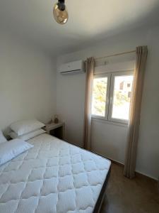 a bedroom with a white bed and a window at Aegean Breeze Kythnos Greek small apartment in Mérikhas