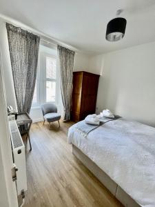 a bedroom with a bed and a chair and a window at The Blue Door in Kirkcudbright