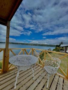 a table and chairs on a deck with a view of the water at Cabaña casa 6 personas, con vista al mar in Dalcahue