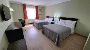 una camera d'albergo con due letti e una televisione di Hotel Diego de Almagro Copiapo a Copiapó