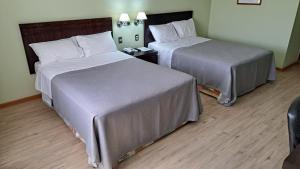 a hotel room with two beds and a night stand at Hotel Diego de Almagro Copiapo in Copiapó