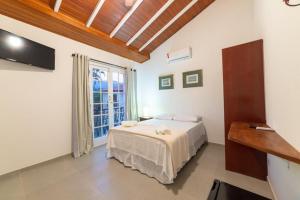 a bedroom with a bed and a large window at Pousada Portal de Paraty in Paraty