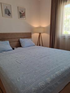 a bedroom with a bed with a blue comforter and a window at Lux Apartment Jovanovic in Tivat
