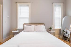 a bedroom with a large white bed with two windows at The Matisse at Wooster Square Yale With Parking in New Haven
