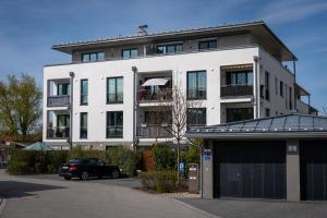 Un bâtiment blanc avec une voiture garée devant. dans l'établissement Design Apartment Alpenvorstadt, à Holzkirchen