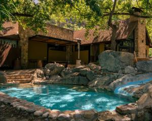 a swimming pool with rocks in a yard at Cabañas Cascada del Barro in Guajuquito