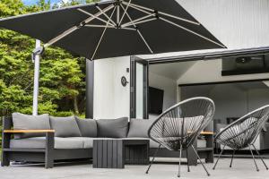a patio with a couch and two chairs and an umbrella at The Ridge in Mangawhai