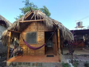 a thatch roofed hut with a hammock outside at El Nómada Hostel in Palomino