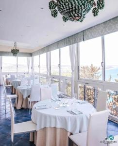 a restaurant with white tables and white chairs and windows at Luna Convento Copanello B&B in Stalettì