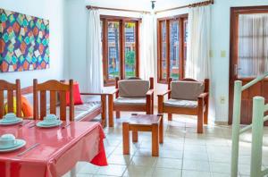 un soggiorno con tavoli, sedie e finestre di Res Village do Bosque 03 a Porto Seguro