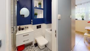 a bathroom with a white toilet and a blue wall at Kotlarska 7 TectumApartments in Wrocław +1 photo