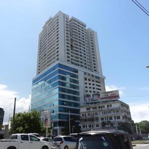 um edifício alto com carros estacionados em frente em Stylish Studio apartment with Pool and Gym em Dar es Salaam