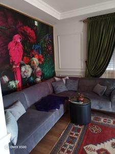 a living room with a couch and a red bird on the wall at Dublex house - near the Airport and sea and in the city in Dalaman