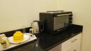 a kitchen counter with a microwave and a yellow pot on a plate at Stylish Studio apartment with Pool and Gym in Dar es Salaam