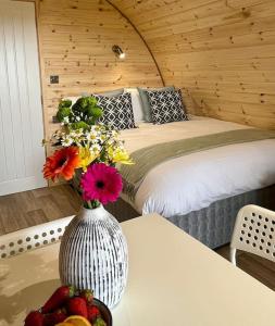 a bedroom with a bed and a vase with flowers on a table at Plumgrove Pod Easkey in Sligo