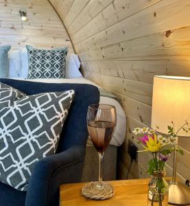 a wine glass sitting on a table next to a bed at Plumgrove Pod Easkey in Sligo