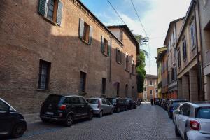 a street with cars parked next to a brick building at Collegio di Spagna 13 in Bologna