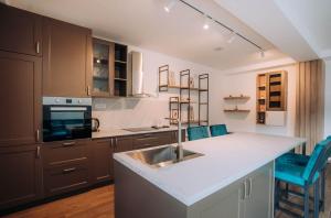 a kitchen with a sink and a counter with blue chairs at Darki Comfort Apartments - Stylish Apartments with Free Parking in Tranquil Area in Ohrid