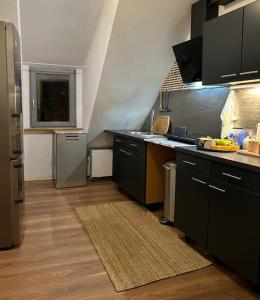 een keuken met zwarte kasten en een aanrecht bij Boho Apartment in der Stadtmitte in Lahr