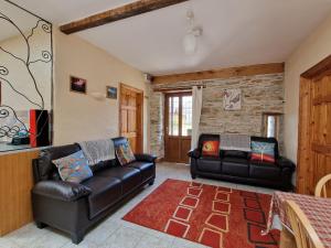 a living room with two leather couches and a rug at Puffin Cottage in Whitland