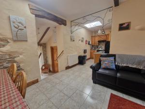 a living room with a couch and a kitchen at Puffin Cottage in Whitland