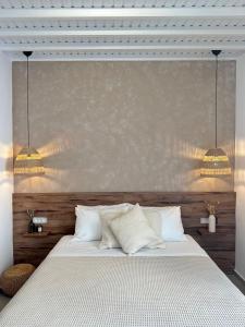 a bedroom with a white bed with two lights above it at Oikia Suites Mykonos in Mýkonos City