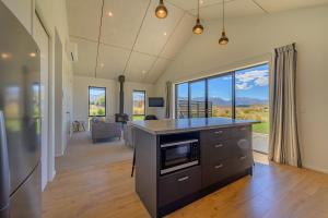 a kitchen with a counter top and a living room at Schist Cabin in Twizel