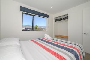 a bedroom with a white bed and a window at Schist Cabin in Twizel