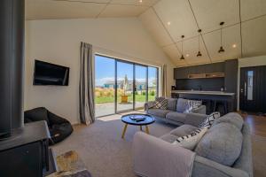 ein Wohnzimmer mit Sofas, einem TV und einem Tisch in der Unterkunft Schist Cabin in Twizel
