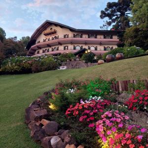 a building with a bunch of flowers in a garden at Hotel das Hortênsias in Gramado